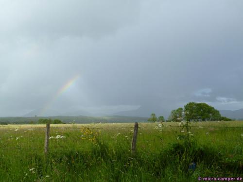 Im Dunst hinter dem Regenbogen zeichnet sich die Vulkankette ab
